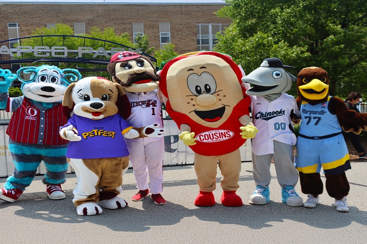 Group of colourful promotional mascot costumes, including animal and character designs, posing together outdoors