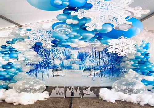 Winter wonderland theme party with snowflake fairy lights and white decor